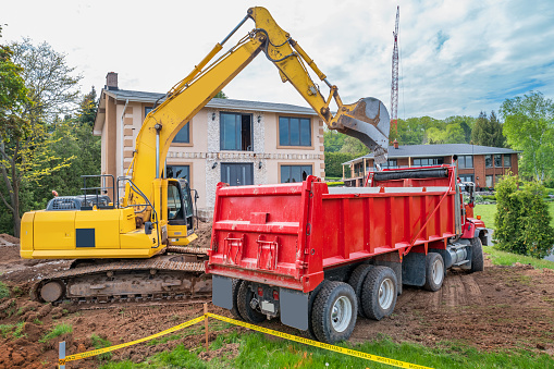 Excavator and hauling truck during the construction of a home addition.