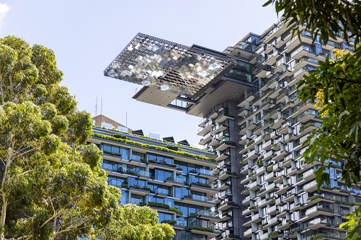 Apartment buildings with vertical gardens and heliostat with motorised mirrors, sky background with copy space, Green wall-BioWall or living wall is a wall covered with living plants on residential tower in sunny day, Sydney Australia, full frame horizontal composition