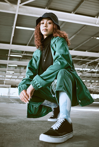 Fashion, beauty and black woman pose in parking lot with trendy, stylish and modern outfit. Portrait of girl with contemporary, edgy and urban style on floor of car park or garage in designer clothes