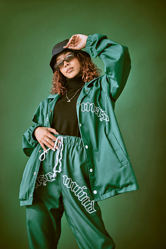 Fashion clothes, style and black woman with green rap, gen z or hip hop aesthetic outfit for cool, edgy or fashionable look. Designer brand apparel, attitude or teen fashion model on green background