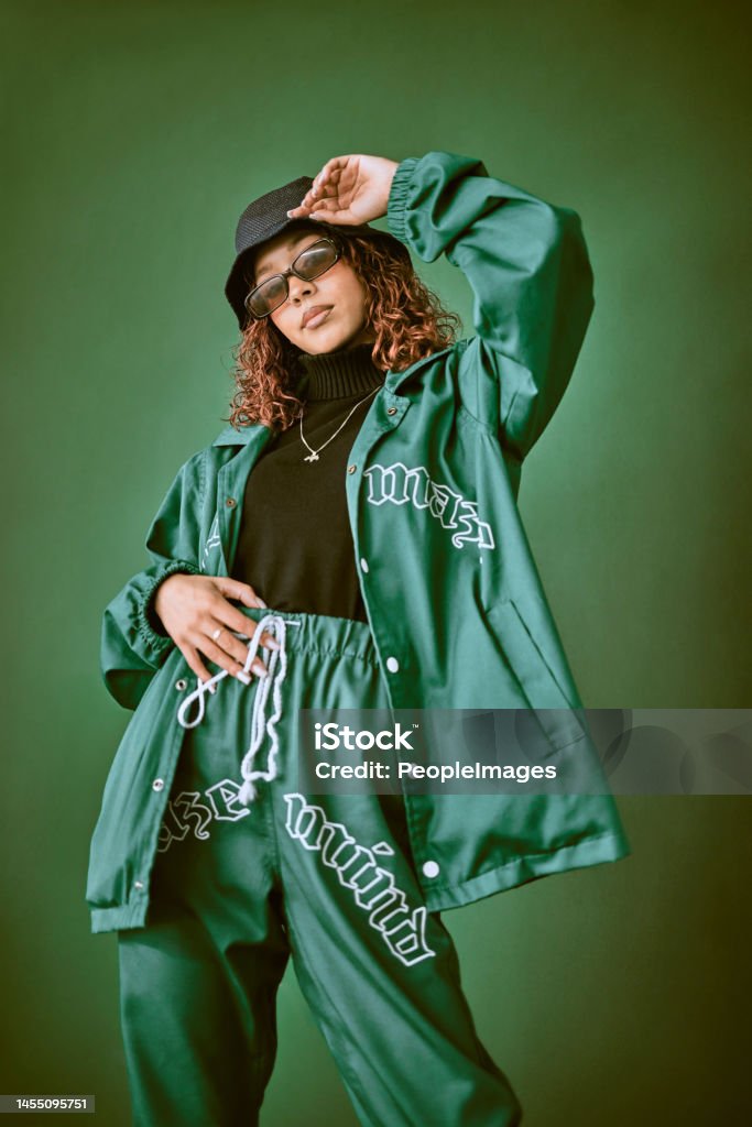 Fashion clothes, style and black woman with green rap, gen z or hip hop aesthetic outfit for cool, edgy or fashionable look. Designer brand apparel, attitude or teen fashion model on green background Fashion Stock Photo