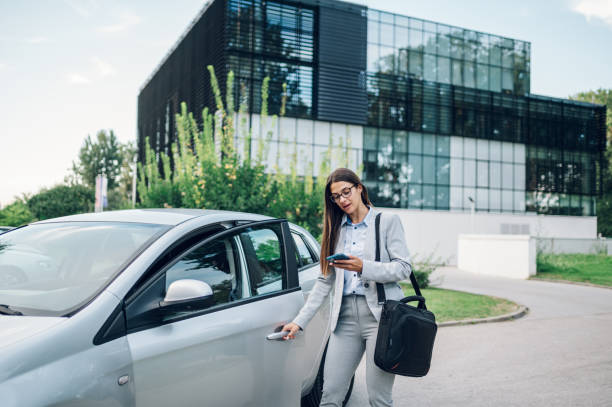 istock Business woman getting into the car and using smartphone 1455097105