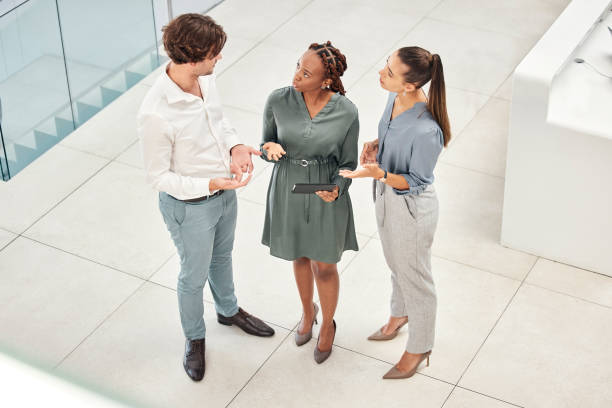istock Top view, tablet and business people in office lobby discussing project, idea or online planning. Teamwork, diversity or employees in corridor working together on tech, research or web surfing online 1455097218