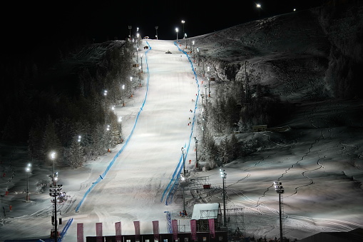 Scenic night view of an illuminated snowy ski track. Night skiing service at Sestriere winter mountain resort