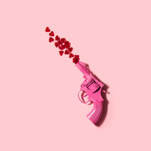 istock Red hearts and gun on pastel light pink background. Minimalistic love concept. Creative Valentine's Day flat lay idea. 1455106955