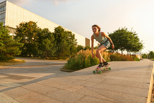Cheerful young woman skateboarding in city park