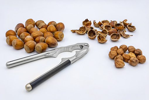 Nutcracker with whole hazelnuts, shells and kernels isolated on white background