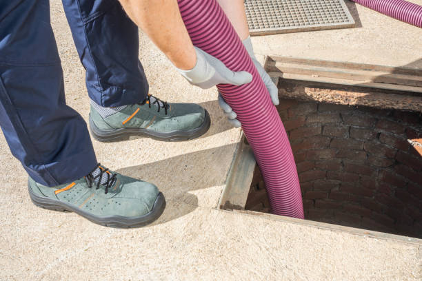 PLUMBER DRAINING AND CLEANING SEWER MANHOLE.