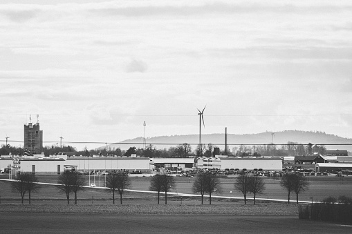 A grayscale beautiful view of the countryside with wind turbines on a cloudy day