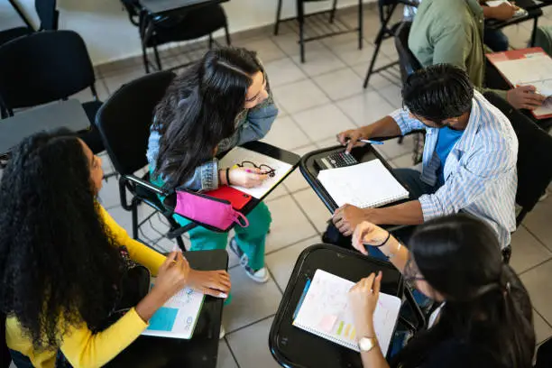 Photo of Circle of young friends studying together in the classroom at university