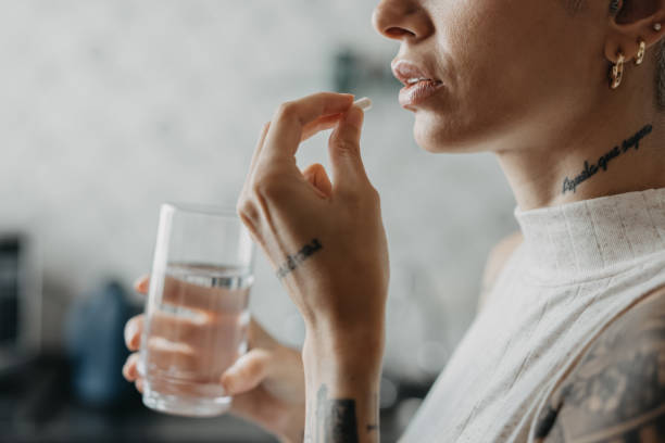 mulher que se medica na medicina de casa - capsule pill white nutritional supplement - fotografias e filmes do acervo