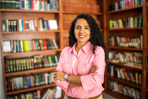 porträt einer lehrerin im mittleren erwachsenenalter in der universitätsbibliothek - professor librarian university library stock-fotos und bilder