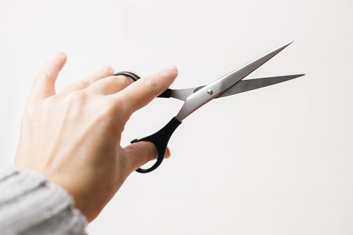 One pair of scissors in the hands of a hairdresser with a black handle on a white background,side view close-up.The concept of tools of a hairdresser,beauty salon,isolate.