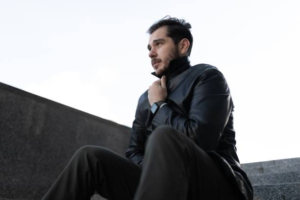 istock upset man sits wrapped in a leather jacket and looks in prostration 1455118538
