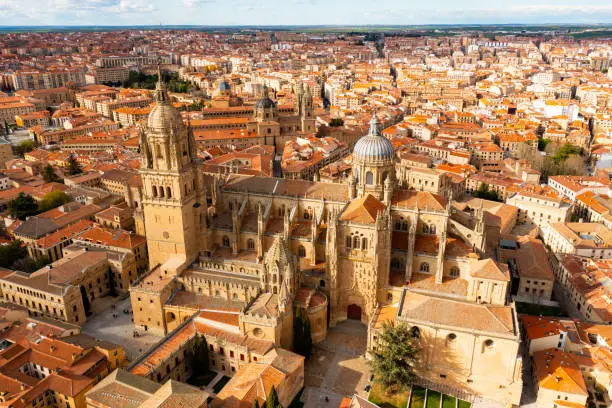 Picturesque architecture of ancient central district of Salamanca with impressive gothic cathedral, baroque domes of Clerecia and Palace de Anaya and terracotta tiled roofs of houses in spring, Spain
