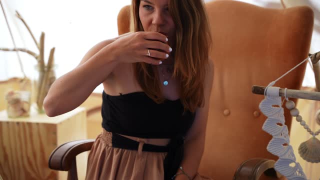Woman drinking tea sitting next to wall hanging decor macrame