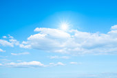 White clouds and sun with sunlight on blue sky.