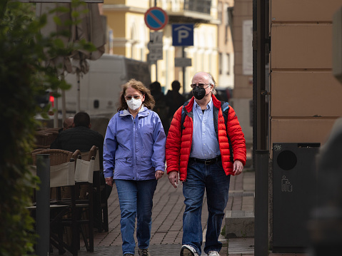 Picture of a white caucasian senior woman and man in Szeged, a city of Szeged while wearing a respiratory face mask during the coronavirus health crisis.