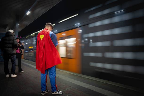 sfocatura selettiva su un uomo che indossa un costume da superman in attesa di un treno della s-bahn di colonia, chiamato anche s-bahn rhein ruhr che passa con speed blur. - superman foto e immagini stock