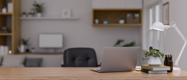 istock Workspace with laptop and copy space on wood tabletop over blurred modern home office 1455136800