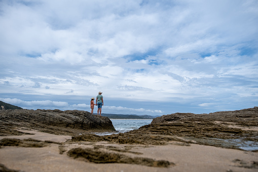 Mother and daughter standing on the rocks by the sea on their summer vacation. Gericke's Point along the Garden Route along in the Western Cape