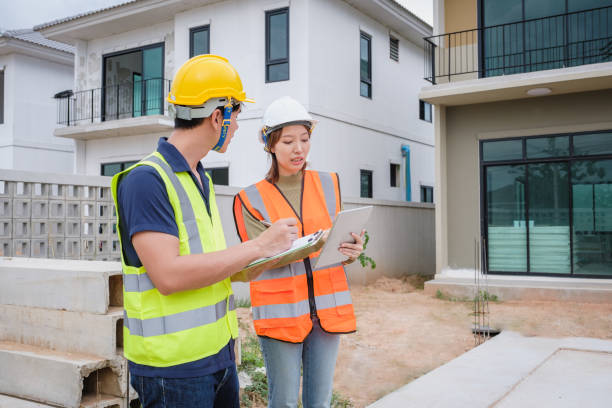istock Construction workers in hardhat on meeting with colleagues discussing a project and checking plans with digital tablet or documents in front of construction site 1455153026