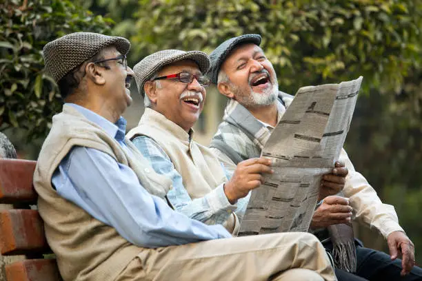Photo of Older male friends reading newspaper at park