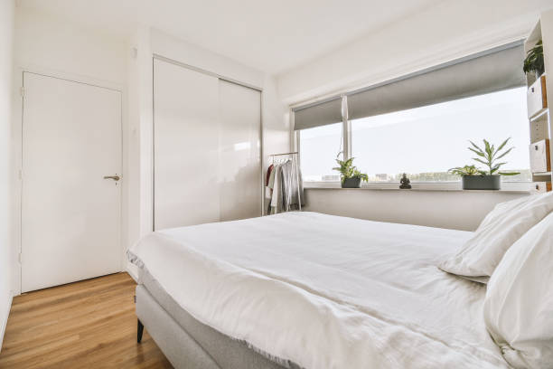 istock a bedroom with a large white bed and a window 1455156130