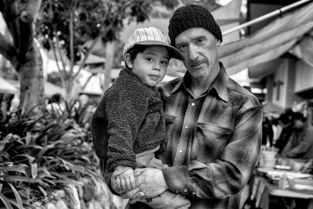 Homeless Drug addict junkie father wearing flannel shirt and beanie holds crying son with baseball cap in park Homeless Drug addict junkie father wearing flannel shirt and beanie holds crying son with baseball cap in park fentanyl addiction stock pictures, royalty-free photos & images