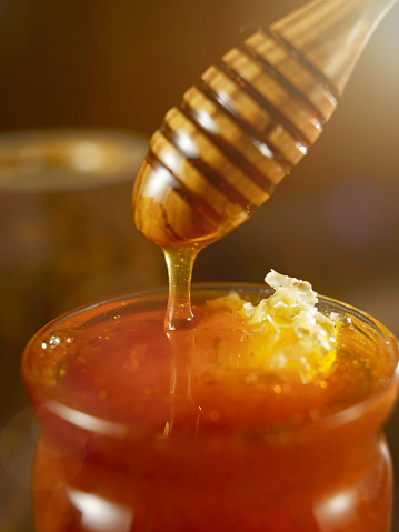 Honey dripping into jar from honey sipper