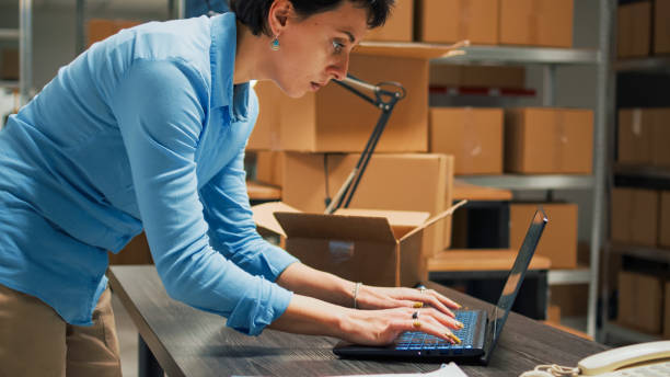 istock Female entrepreneur using warehouse supplies to put in cardboard boxes 1455159772
