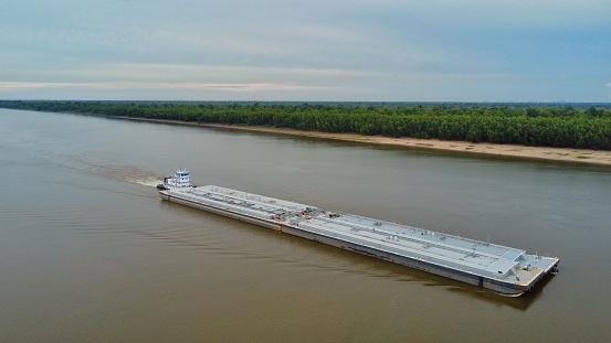 An aerial view of a barge on the Mississippi river with a blue sky in the background