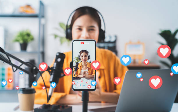 \Vlogger live streaming podcast review on social media, Young Asian woman use microphones wear headphones with laptop record video. Content creator concept. stock photo