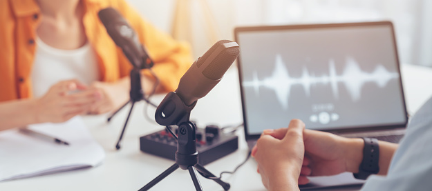 Joven asiática usa micrófonos usa auriculares con computadora portátil graba podcast entrevista para radio. Concepto de creador de contenido. photo