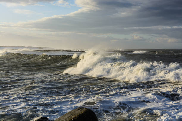 violent steep waves crashing onto a sandy beach during winter. Shot in Denmark