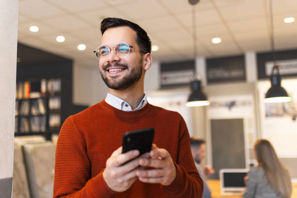 istock Smiling businessman text messaging on smart phone 1455178054