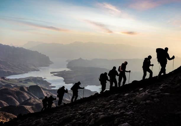 siluetta degli escursionisti all'alba - exploration mountain teamwork mountain peak foto e immagini stock