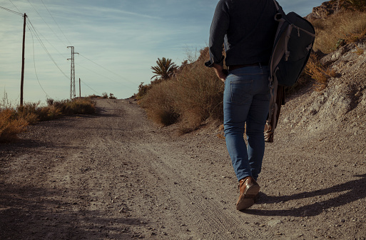 Rear view of adult man walking on dirt road