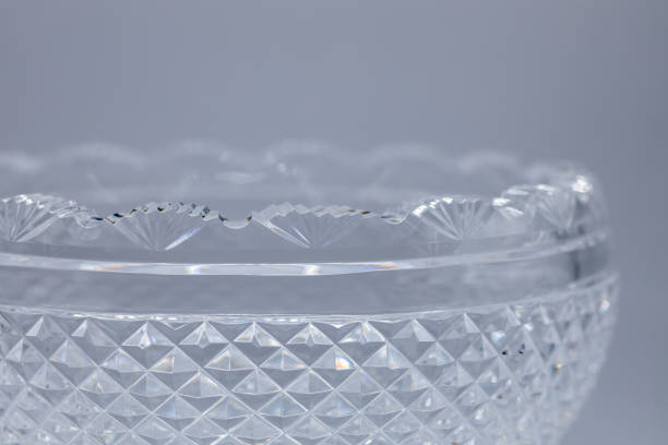 Macro texture view of a lead crystal glass bowl with diamond cuts and scallop edge This image shows a defocused macro texture view of a shimmering antique lead crystal glass bowl with light reflecting diamond cuts and a scalloped edge. lead cut glass crystal stemware stock pictures, royalty-free photos & images