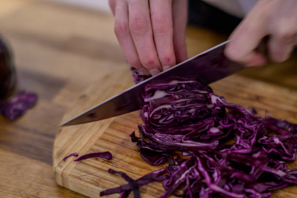 istock Cutting red cabbage with a kitchen knife on a wooden cutting board 1455181350