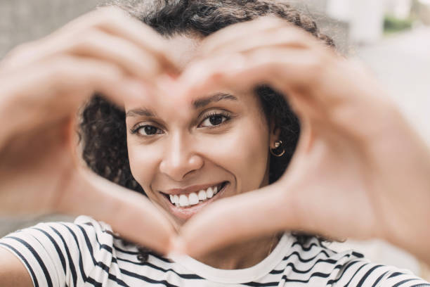 istock Smiling woman making a heart shape with hands closeup 1455181381