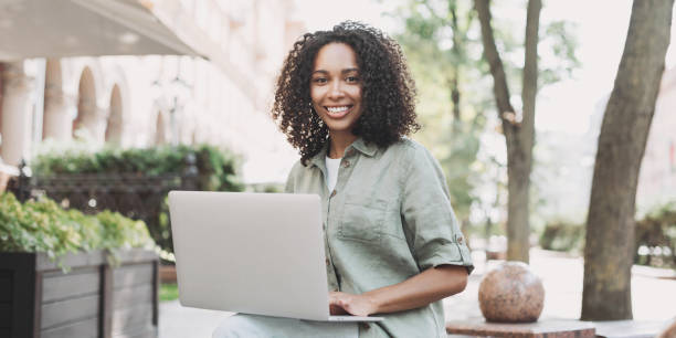 istock Happy woman using laptop in a city 1455181383