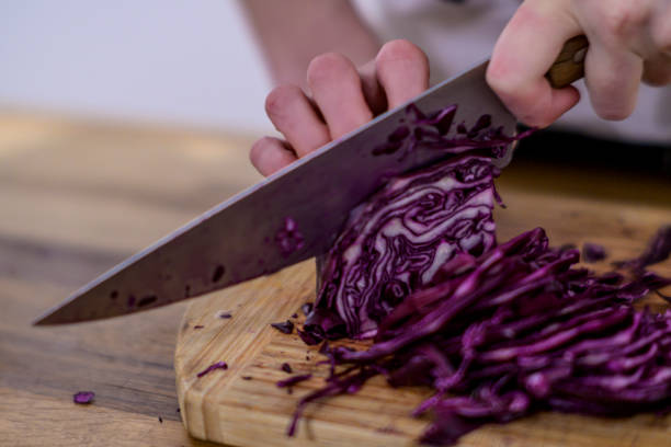 istock Cutting red cabbage with a kitchen knife on a wooden cutting board 1455181391