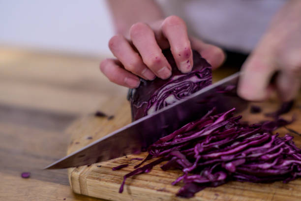 istock Cutting red cabbage with a kitchen knife on a wooden cutting board 1455181444
