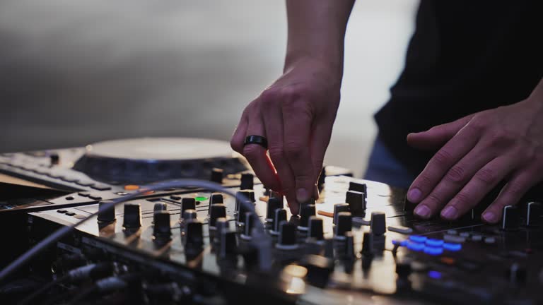 Hands of male Dj operating sound mixer