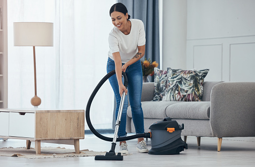 Black woman vacuum cleaner, smile in living room and cleaning tiles floor in home for hygiene. Woman cleaner, happy with appliance for housekeeping work on flooring in house for dust or dirt indoors