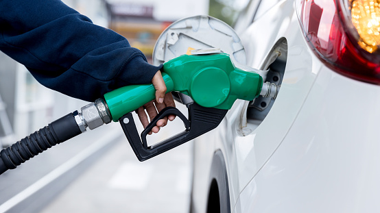 Car fueling at gas station. Refuel fill up with petrol gasoline. Petrol pump filling fuel nozzle in fuel tank of car at gas station. Petrol industry and service. Petrol price and oil crisis concept.