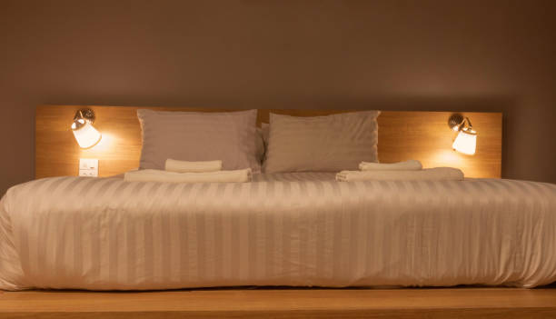 istock white pillows and blanket in bed with light from lamps at night 1455184160