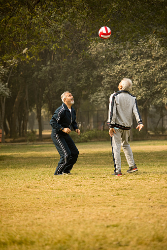 Two old men having fun throwing and catching sports ball at park