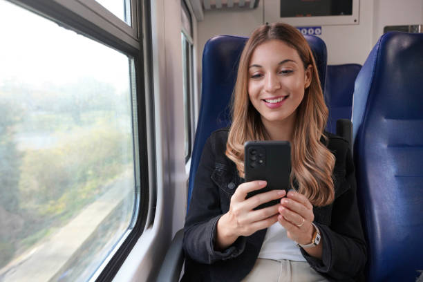 donna d'affari sorridente che utilizza i mezzi pubblici, seduta con il cellulare sul treno - autobus italy foto e immagini stock